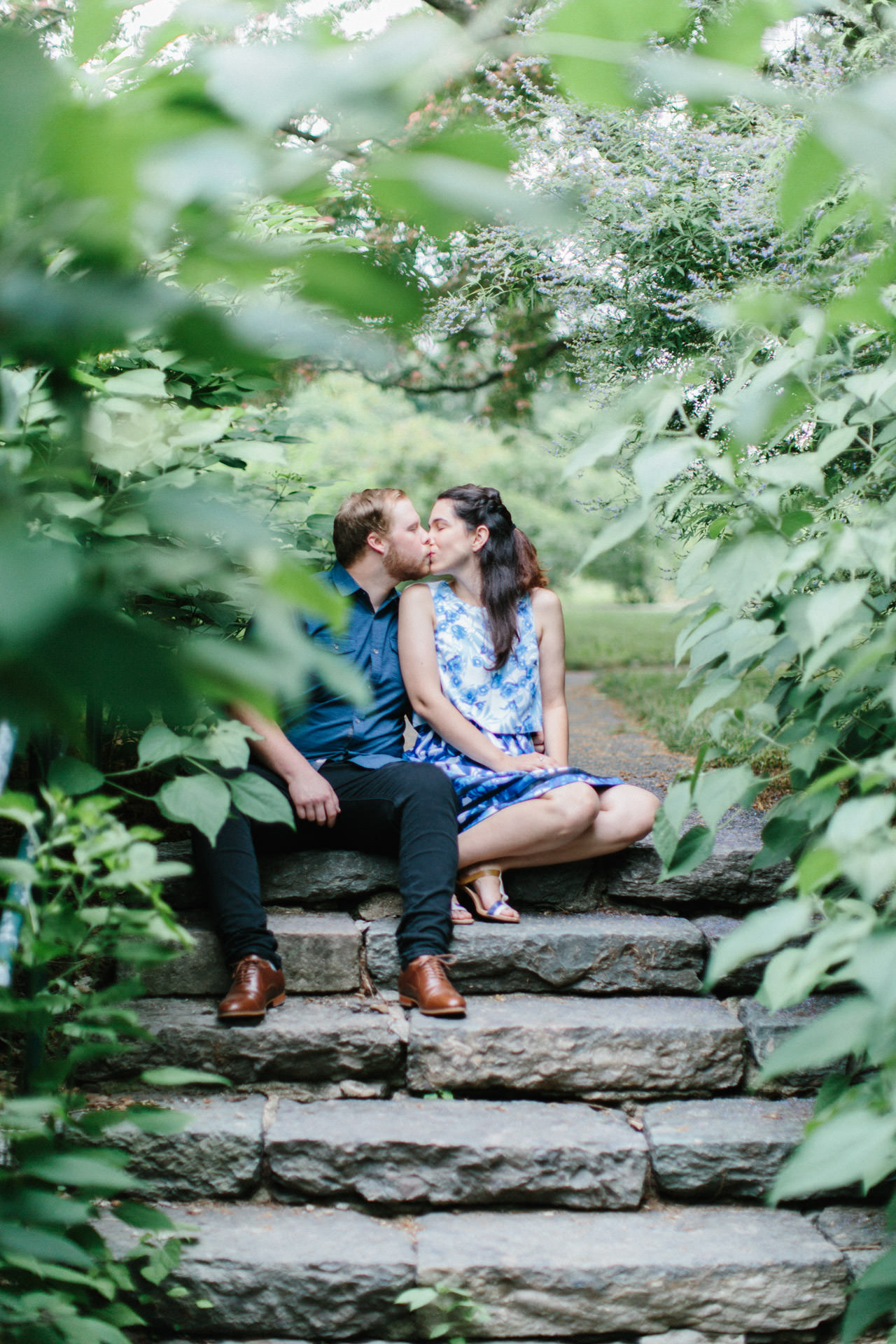 Couple kissing for an engagement photograph at Arnold Arboretum at Harvard University in Boston, MA