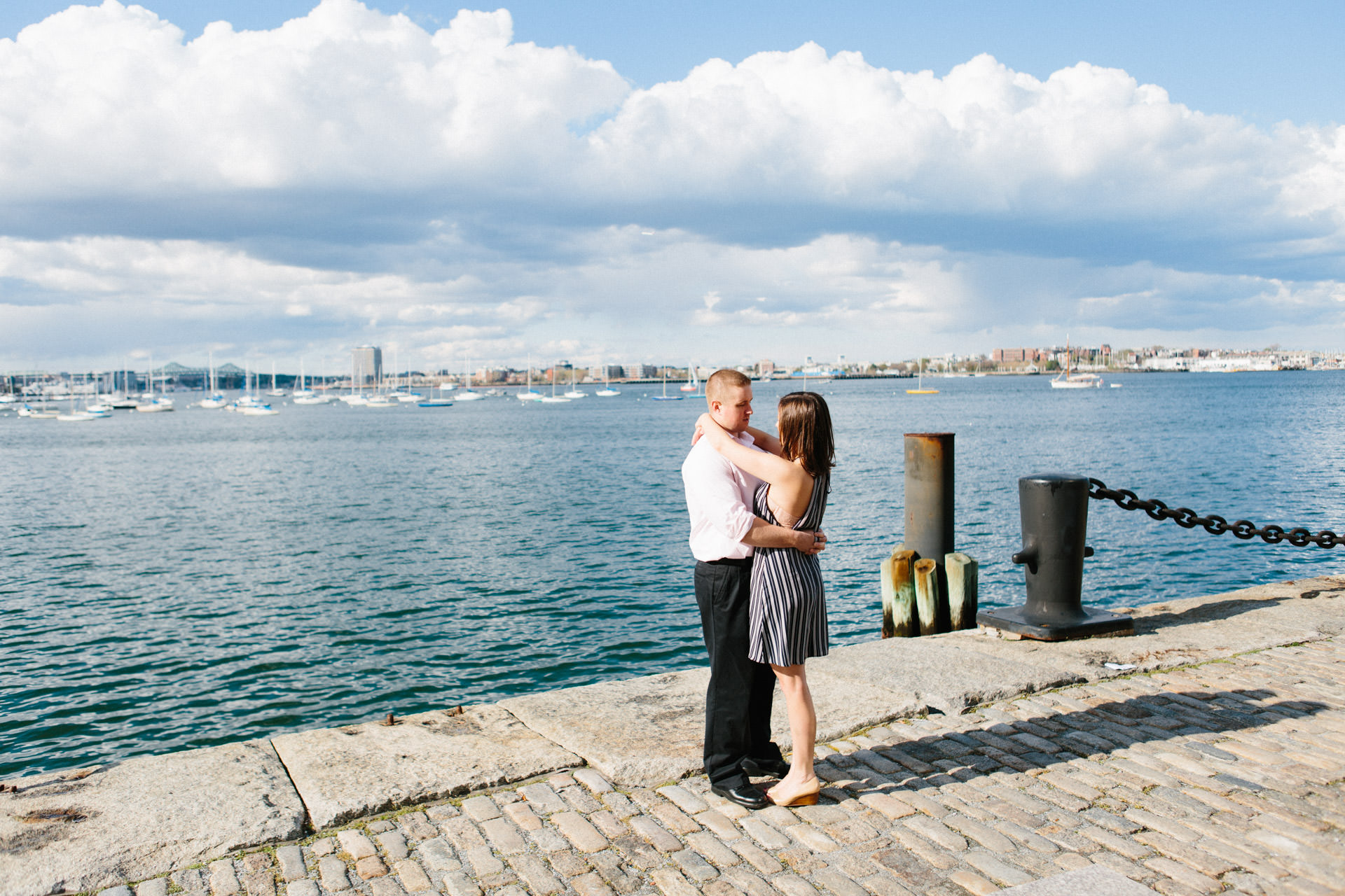 Couple posing for an engagement photograph on the Boston Harborwalk in Boston, MA