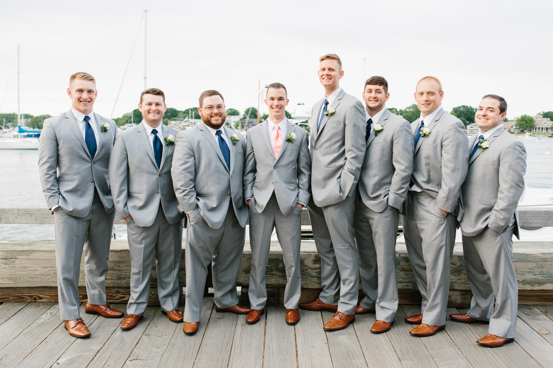 Groom and groomsmen smiling on a peer during his Boston wedding