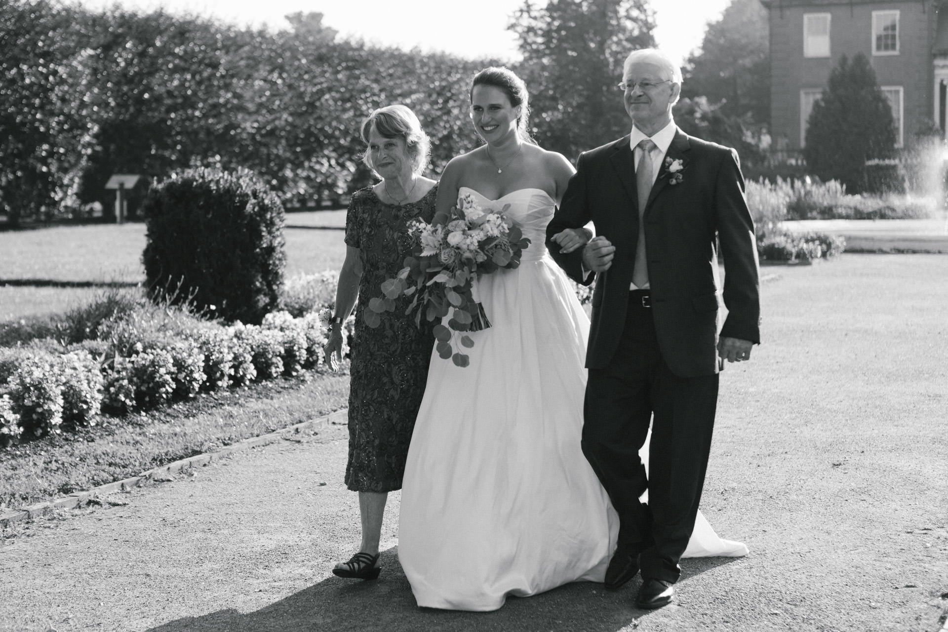 Bride walking down the aisle with her parents during her Boston wedding