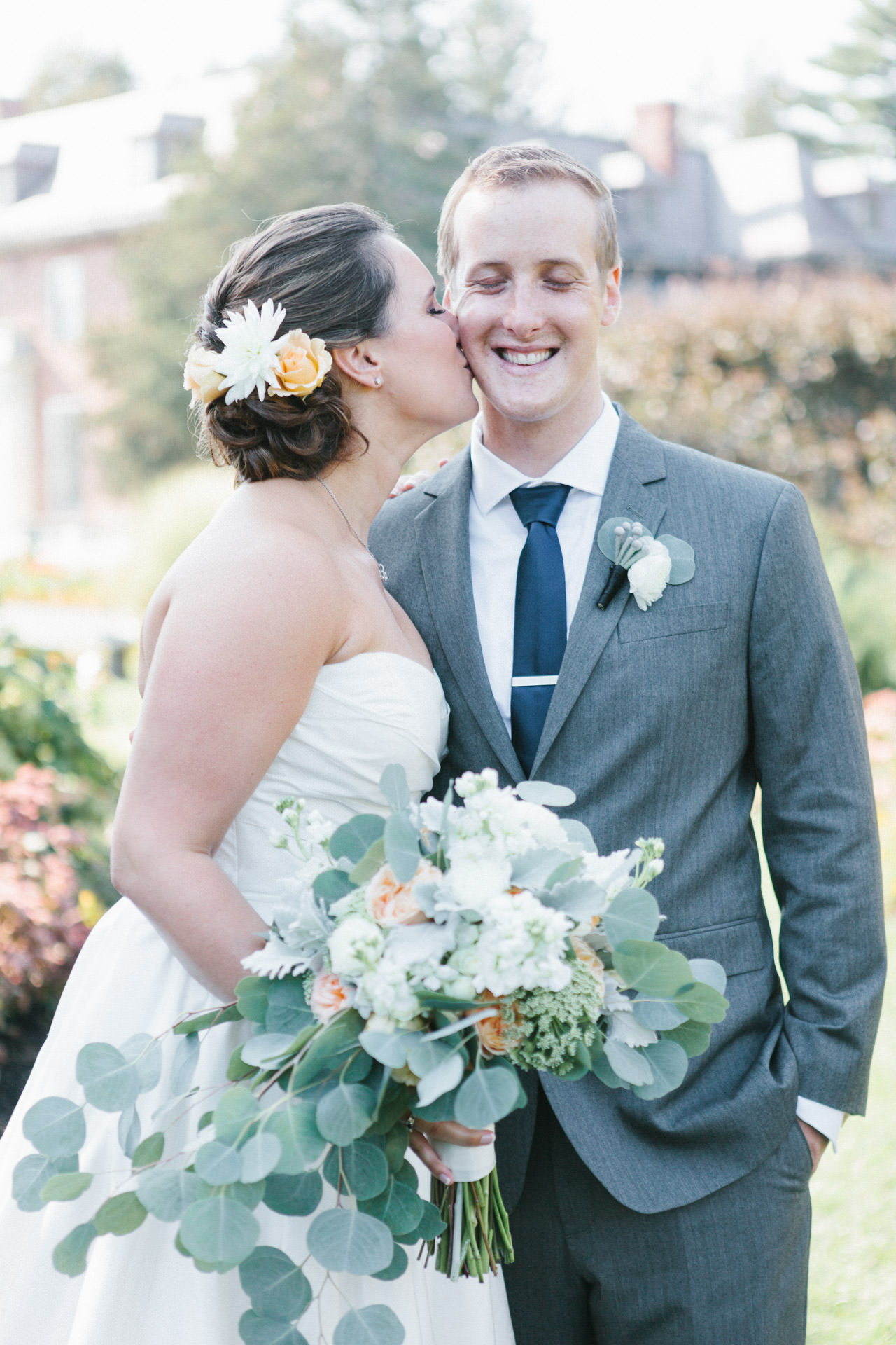 Bride kissing her new husband while holding a flower bouquet