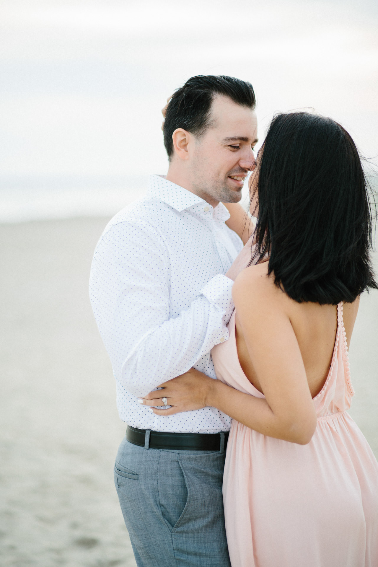 Engaged couple whispering to each other at Horsneck Beach in Westport, MA