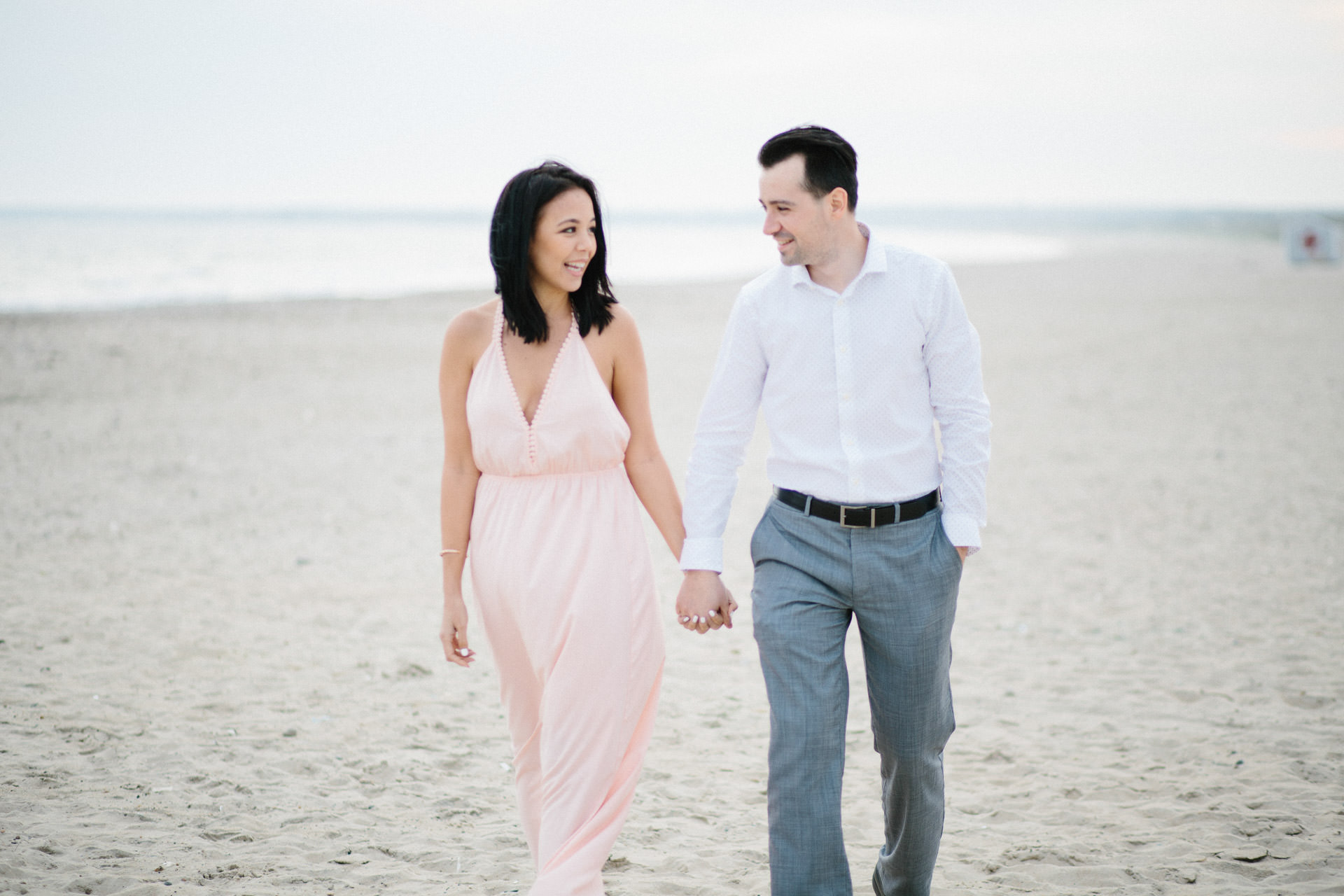 Engaged couple holding hands and walking at Horseneck Beach in Westport, MA