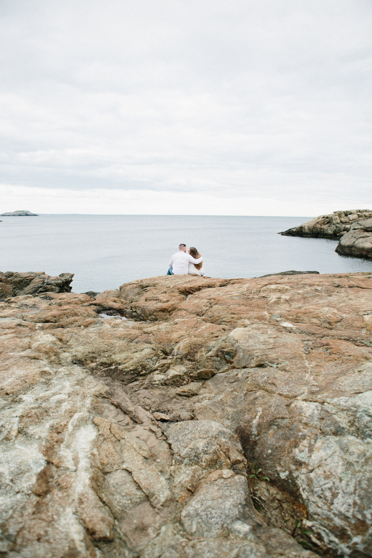Couple embracing during their engagement photo shoot in Nahant Beach in Nahant, MA