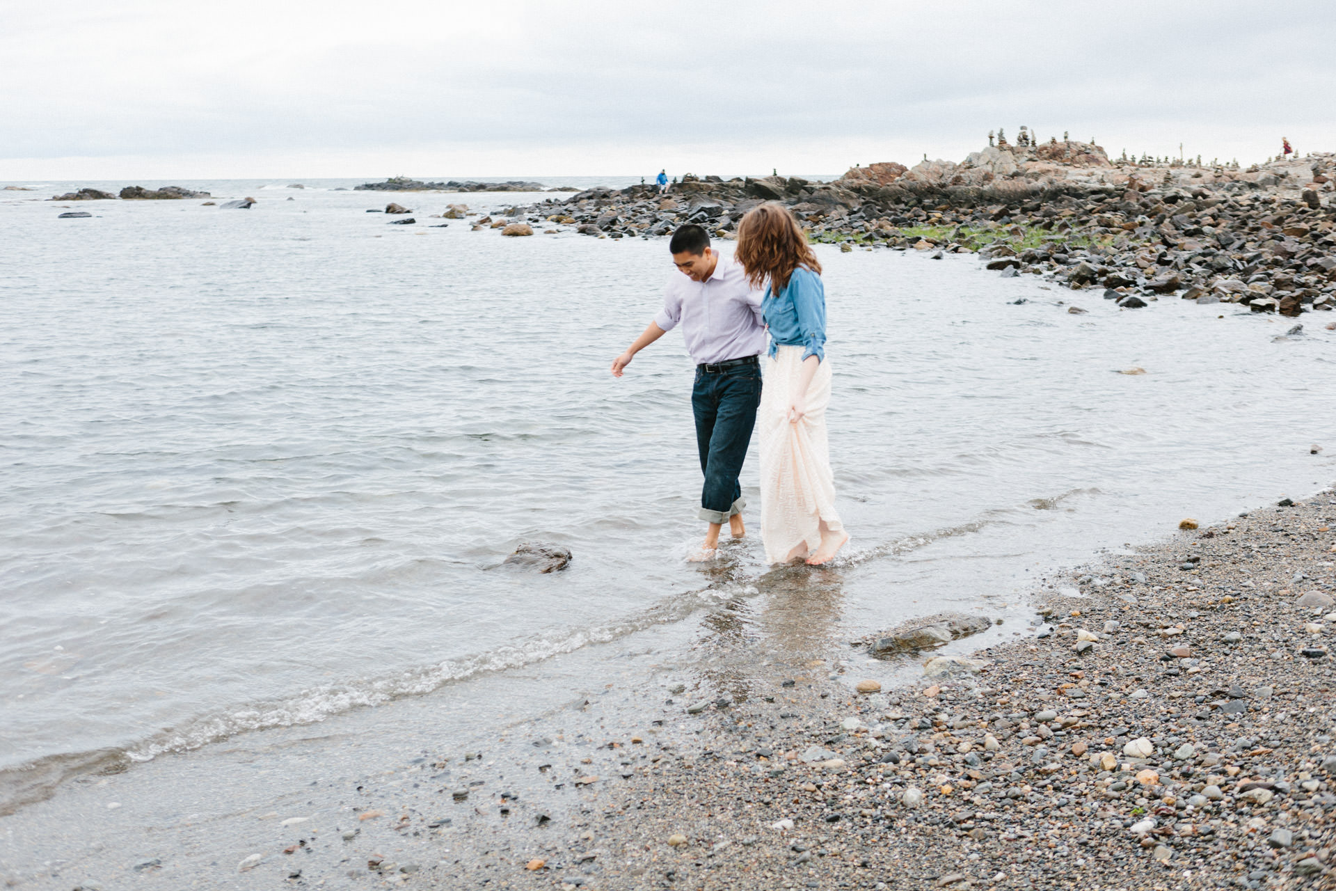 Engaged couple walking on the beach at Odiorne Point State Park in Rye, NH
