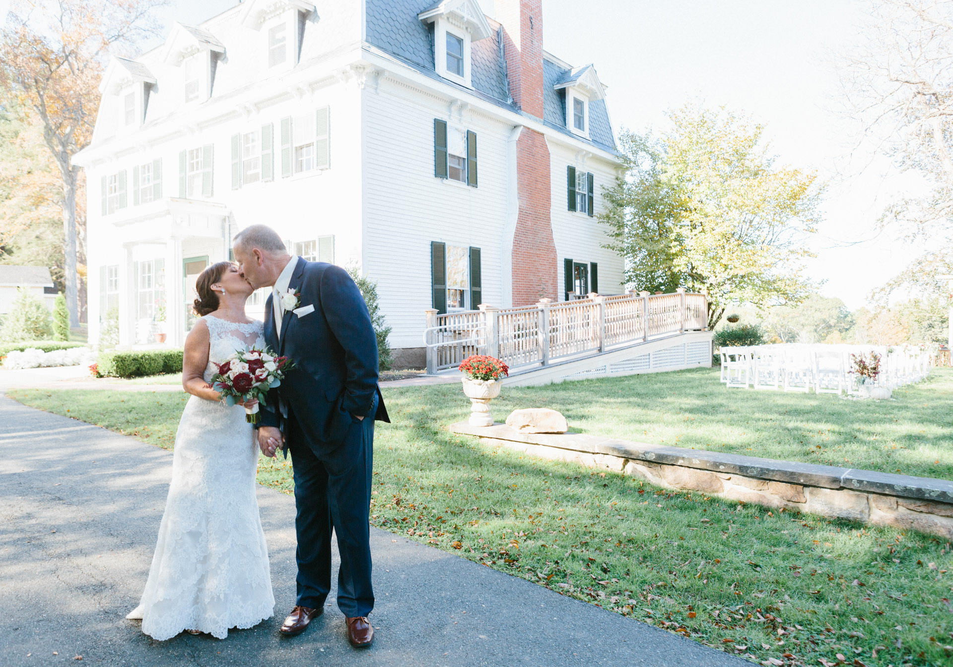 Bride and groom kissing in front of mansion during their Boston wedding