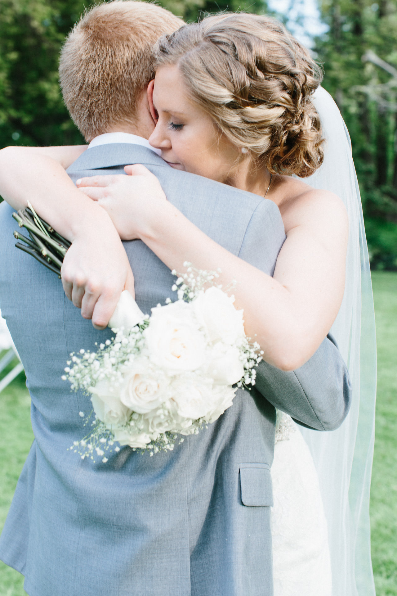 Bride holding her floral bouquet and hugging her new husband